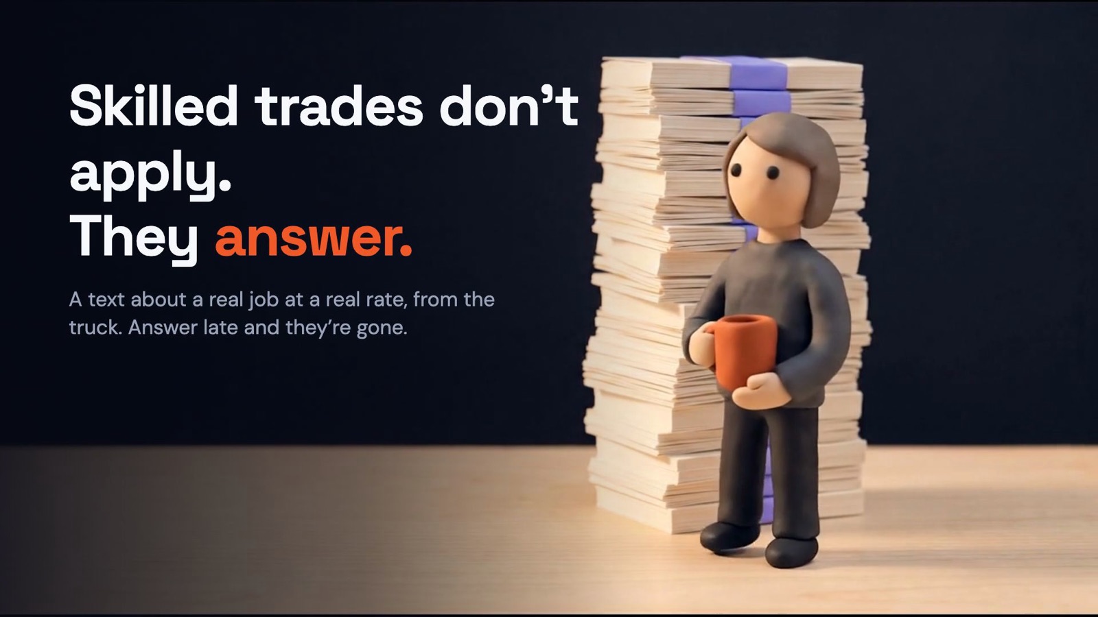 A clay figure holding a coffee mug stands next to a tall stack of paper resumes, beside the words: Skilled trades don't apply. They answer.